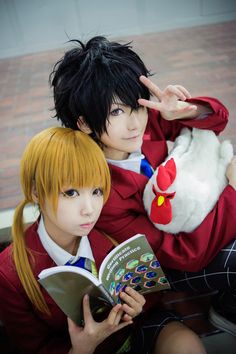 two people dressed as anime characters are posing for the camera and one is reading a book