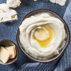 a bowl filled with mashed potatoes and butter on top of a blue table cloth