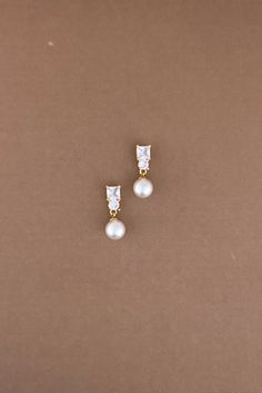 pair of pearl and diamond earrings on brown background