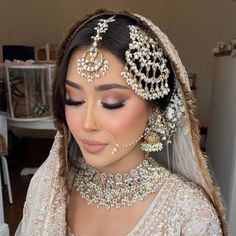 a woman in a bridal gown with jewelry on her head and veil over her face