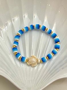 a blue and gold beaded bracelet with a turtle charm on it's end