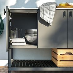 an open cabinet with dishes and utensils in it next to a planter