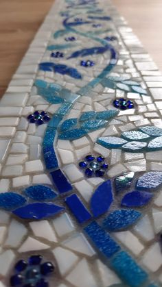 a blue and white mosaic tile design on a wooden table with water droplets running down it