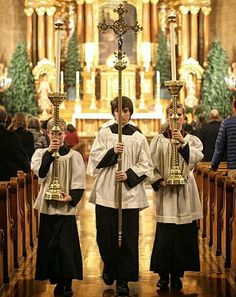 two young boys holding candles in front of the alter