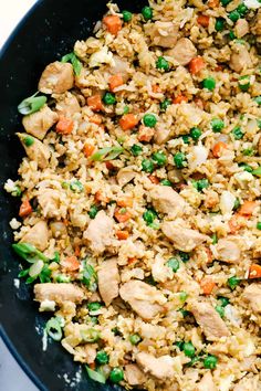 chicken and rice in a skillet with peas, carrots, and celery