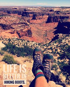 a person with their feet up in the air on top of a cliff overlooking canyons