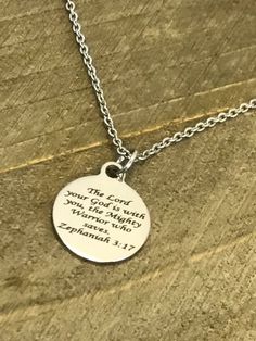 This beautiful necklace is a stainless steel laser engraved pendant with the Zephaniah 3:17 Bible Verse on it to remind the wearer that the Lord is with them. The pendant comes on a stainless steel chain. This pendant is available on your choice of 16, 18, 20, 22, 24, 26, 28 or 30 inch chain. The pendant is also available for individual purchase if you have another chain on which you would like to wear it. This necklace is made of stainless steel to withstand regular wear without tarnishing or c Inspirational Silver Necklace For Father's Day, Inspirational Silver Stainless Steel Jewelry, Meaningful Engraved Stainless Steel Necklace, Inspirational Silver Stainless Steel Necklaces, Inspirational Silver Stainless Steel Necklace, Meaningful Silver Stainless Steel Necklace, Silver Round Charm Necklace With Laser Engraving, Silver Charm Necklace With Laser Engraved Round Pendant, Silver Laser Engraved Charm Necklace