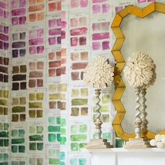 two vases sitting next to a mirror on top of a mantle in front of a colorful wall