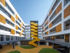 an apartment building with yellow and white balconies on the outside, grass in front