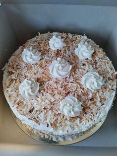 a cake in a box with white frosting and coconut toppings on the top