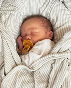 a baby wrapped in a blanket with a pacifier in it's mouth, sleeping