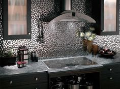 a stove top oven sitting inside of a kitchen next to a vase with flowers on it