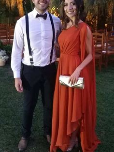 a man and woman standing next to each other in formal wear at an outdoor event