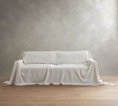 a white couch sitting on top of a hard wood floor next to a gray wall