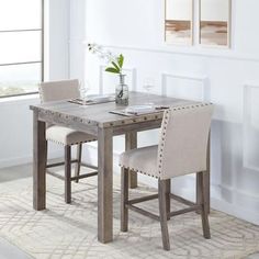 a dining room table with two chairs and a vase