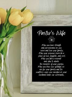 a vase filled with yellow flowers next to a white framed sign that says pastor's wife