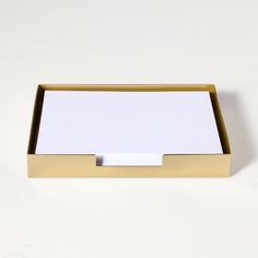 a white and gold business card holder on a white surface with an empty note pad in the middle