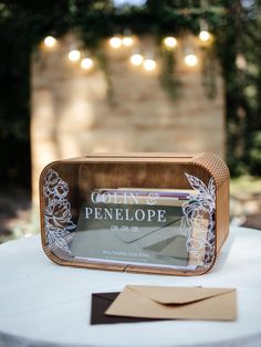 a table topped with a wooden box filled with envelopes and string lights hanging from the ceiling