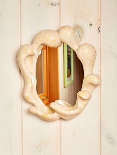 a mirror hanging on the side of a white wooden wall next to a door and window