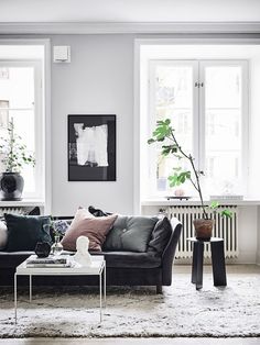 a living room filled with lots of furniture next to two windows and a rug on the floor