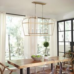 a dining room table with chairs and a vase on top of it in front of a window