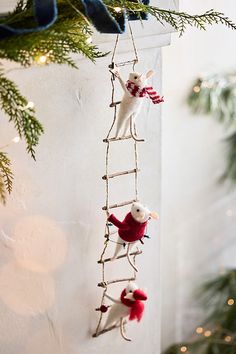 an ornament hanging from a christmas tree with two mice on the ladders