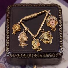 An elegant Art Nouveau charm (circa 1900-1910). This lovely 10k gold charm features with closed eyes and a pearl in her headdress. The charm was originally an antique stick pin that we transformed with the addition of a 10k gold jump ring bail. The charm measures 0.7 inches from the top of the jump ring bail to the bottom of the charm by 0.4 inches wide. It is in good condition; however there is a chip to the nacre of the pearl visible under magnification. Materials: 14k gold, pearl. Antique Yellow Gold Brass Charms, Antique Brass Charms For Collectors, Victorian Vintage Charm In Yellow Gold, Victorian Yellow Gold Vintage Charm, Ceremonial Yellow Gold Jewelry With Charms, Elegant 14k Gold Collectible Charms, Elegant 14k Gold Charms For Collectors, Victorian 14k Gold Jewelry With Vintage Charm, Vintage 14k Gold Charms For Gift