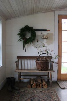 a wooden bench sitting next to a door with a wreath on the wall above it