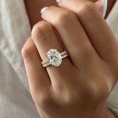 This exquisite engagement ring set showcases a brilliant 3-carat oval lab-grown diamond, complemented by the shimmering beauty of pave-set diamonds. The oval diamond radiates exceptional quality with its brilliant cut facets, while the hidden halo design frames it with smaller accent diamonds, creating a mesmerizing effect. The band itself is adorned with french pave diamonds, adding a sparkling brilliance that enhances the ring's overall allure. Each diamond is securely set in a shared prong se Two Wedding Bands With Engagement Ring Bridal Sets, Oval Shaped Engagement Rings White Gold, Oval Diamond Band Engagement Ring, Oval Diamond Ring With Diamond Band, French Pave Oval Engagement Ring, Rose Gold Wedding Ring Oval, Oval Engagement Ring With Accent Band, Raised Oval Engagement Ring, Wedding Ring Set Oval Diamond