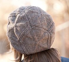 a woman wearing a gray hat with braids on her hair and back to the camera