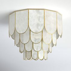 a chandelier hanging from the ceiling with white and gold trimmings on it