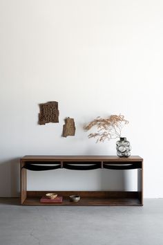 a wooden shelf with two vases on top of it next to a white wall