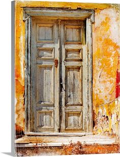 an old wooden door in front of a yellow wall