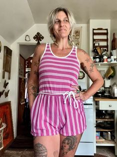 Ugh this is so cute but so short for my torso Amazing 80's striped romper  Magenta purple and white striped romper  Tank sleeves with cute buttons on top of sleeves  Elastic waistline  Ties around the waist it's connected in back  One pocket on one side  Cotton polyester material  Great vintage condition  Short shorts  Tag reads size medium  Measurements are approximate and taken flat so please double bust waist and hips for more accurate sizing  Bust: 15.5 in  Waist: 15.5 in stretched to 17 in Purple Relaxed Fit Sleepwear For Summer, Striped Sleepwear For Summer Loungewear, Retro Pink Summer Jumpsuits And Rompers, Retro Pink Jumpsuits And Rompers For Summer, Pink Retro Summer Jumpsuits And Rompers, Summer Striped Cotton Jumpsuits And Rompers, Spring Striped Cotton Jumpsuits And Rompers, Casual Striped Jumpsuits And Rompers For Loungewear, Striped Cotton Jumpsuits And Rompers For Spring