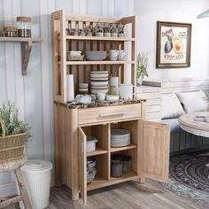 a kitchen area with wooden shelves and dishes on the counter, next to a couch