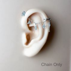 a pair of ear piercings on top of a white surface with the words chain only written below it