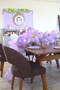 a dining room table with purple balloons on it