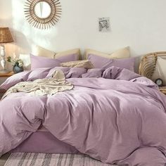 a bed with purple sheets and pillows in a room