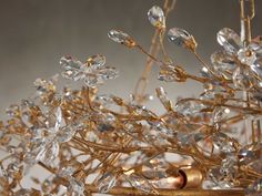 a gold chandelier with crystal flowers and leaves hanging from it's sides