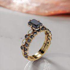 a gold ring with black and white stones on it, sitting on top of a table