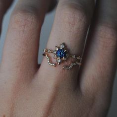 a woman's hand with a ring on it that has a blue stone in the middle