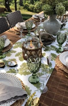 the table is set with dishes, glasses and silverware for an outdoor dinner party