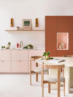 a kitchen with pink cabinets and white flooring, including a round dining table surrounded by beige chairs