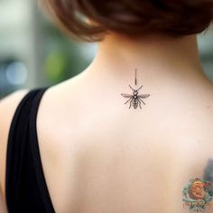 the back of a woman's neck with a bee tattoo on her left shoulder