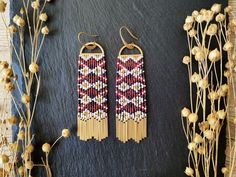 two pairs of beaded earrings sitting on top of a table next to dried flowers