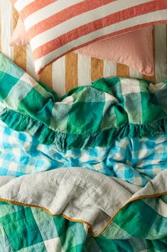 an unmade bed with green and white checkered sheets