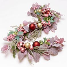 two christmas wreaths decorated with ornaments and greenery