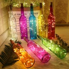 wine bottles with lights in them are sitting on the floor next to a pine cone