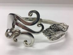 two silver bracelets sitting next to each other on a white surface with an animal's head in the middle