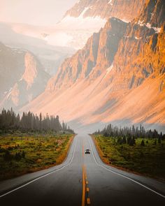 a car driving down an empty road with mountains in the background